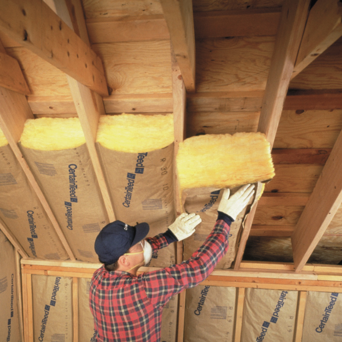 Fiberglass Batt Insulation being installed in an attic roof.