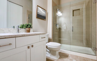 Transitional bathroom interior design in soft beige colors. Features glass shower with taupe tile surround and white vanity.